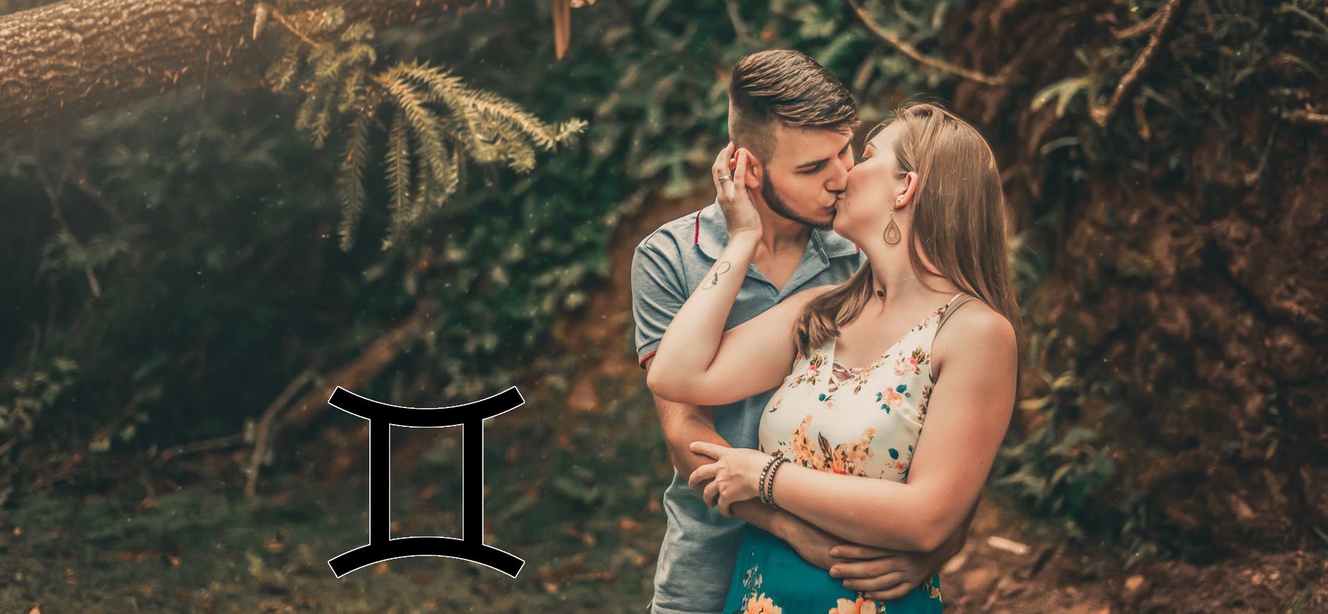 A Gemini man kisses a woman in the forest.